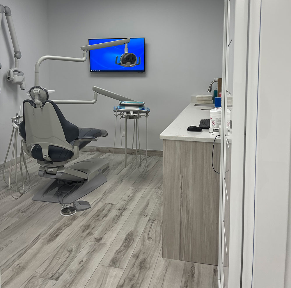 The image depicts a dental office interior, featuring a dental chair with a patient s headrest, a modern dental chair, a computer monitor showing an image of teeth, and other dental equipment.