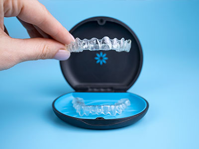Innovative oral care device, a dental impression kit with a clear plastic tray and a blue lid, displayed against a light blue background.