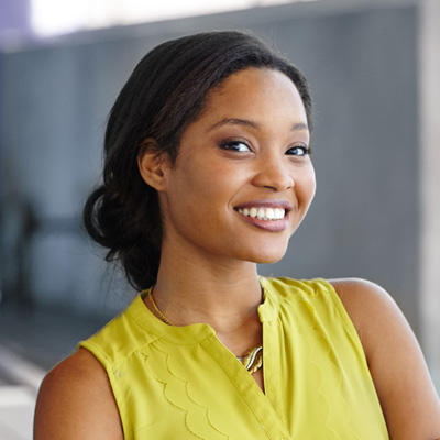 Smiling woman in a yellow top posing for a portrait.