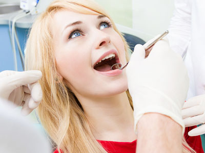 The image shows a woman in a dental chair receiving dental care, with a dentist performing a procedure and the woman's mouth open.