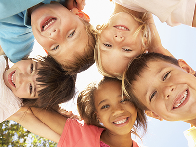 A group of children, both boys and girls, are smiling at the camera, arranged in a semi-circle.